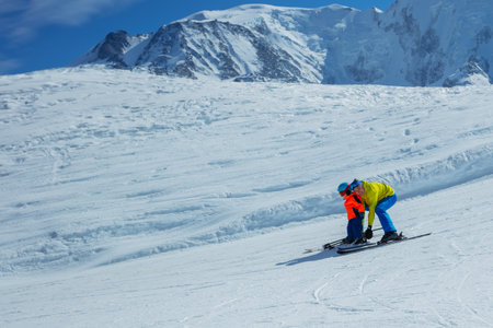 Father teach boy glide behind hold ski bindings with handsの写真素材