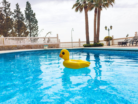 Inflatable funny toy duckling swim in blue swimming poolの写真素材