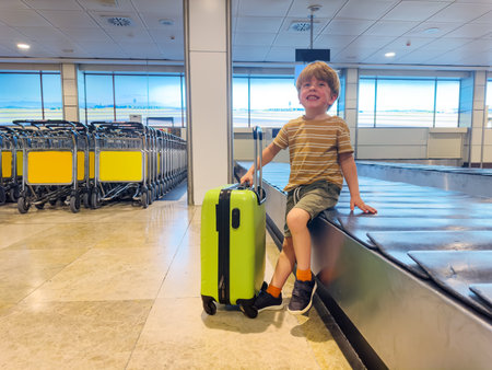 Small boy patiently waits for checked bag at baggage conveyorの写真素材