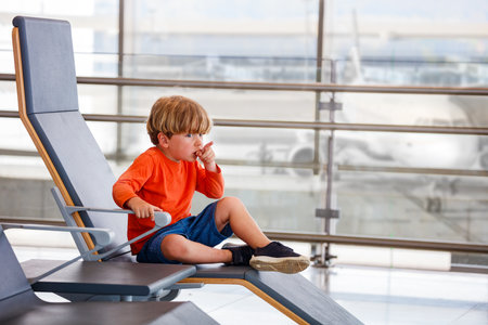 Boy waits for flight, points at planes in airport loungeの写真素材