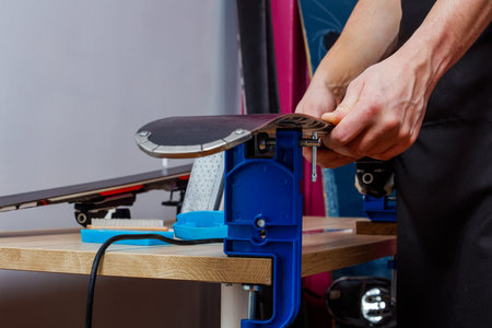 Close up of mans hands checking ski on vises ready to repairの写真素材