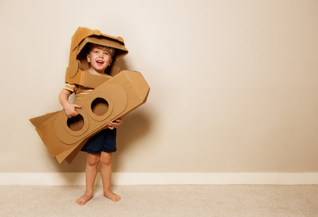 Young boy holds cardboard rocket, imagines space voyageの写真素材