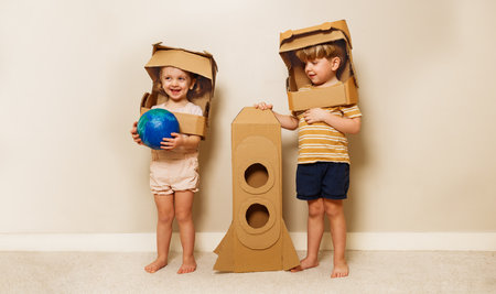 Happy kids play astronauts hold earth model and cardboard rocketの写真素材