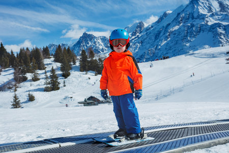 Boy in ski mask and helmet on moving walkway at winter schoolの写真素材