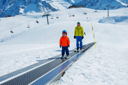Little boy and a dad go up on the ski moving walkwayの写真素材