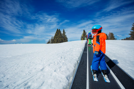 Two boys on the ski moving walkway belt at skiing schoolの写真素材