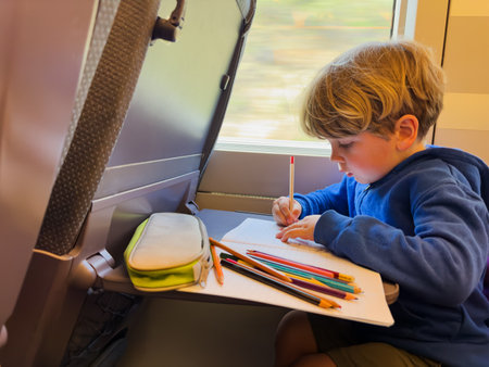 Child on high-speed train draws and writes in the notebookの写真素材