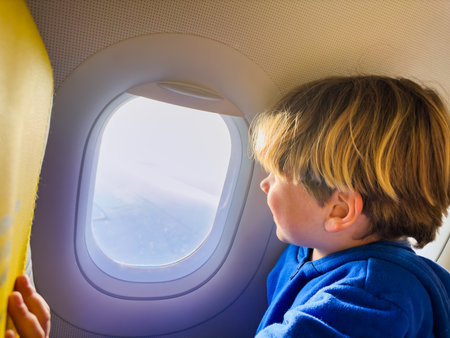 Handsome little boy sit and look at the window in planeの写真素材