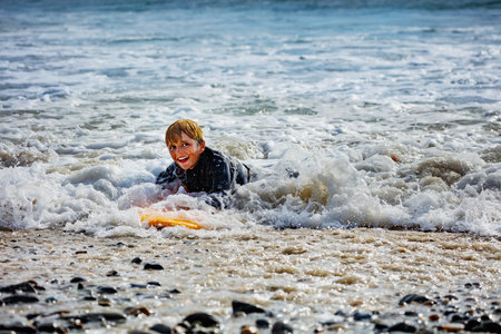 Boy with surfboard get to shore after surfing smiling