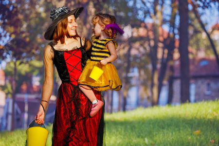 Mother holding little girl in witch and bee Halloween costumesの写真素材