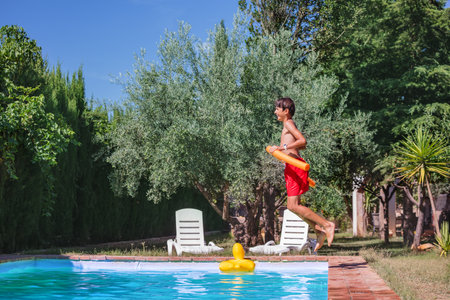 Teen wear red shorts jump to sunny swimming pool profile viewの写真素材