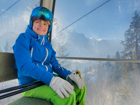 Teen kid in blue ski coat enjoys alpine view from cable carの写真素材