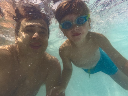 Fun underwater selfie of father and his son at swimming poolの写真素材