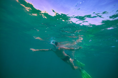 Adventurer in aquatic gear spread arms snorkeling underwaterの写真素材