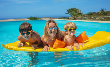 Mother with kids enjoying pool time float on yellow mattressの写真素材