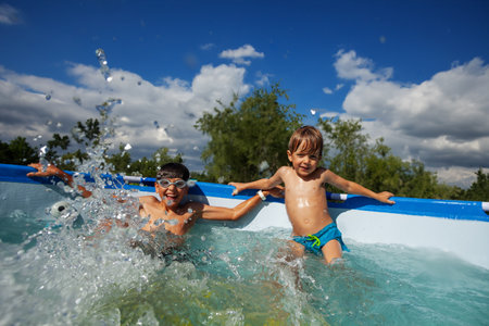 Happy siblings enjoying their time in a domestic swimming poolの写真素材