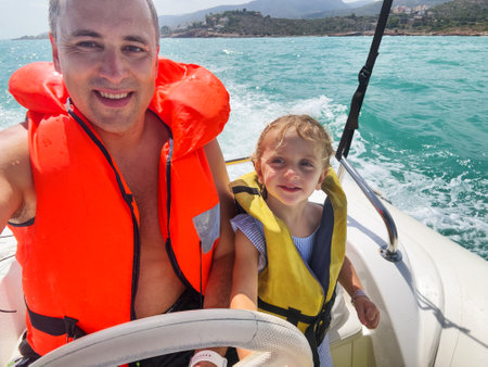 Father and his daughter enjoying a vacations boat ride at seaの写真素材