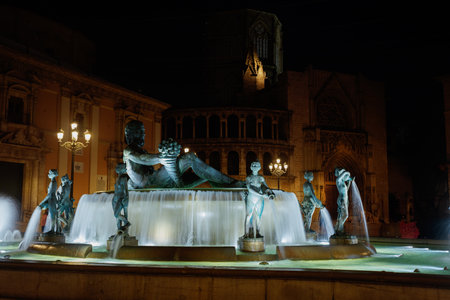 Illuminated statue fountain and historical architecture backdropの写真素材