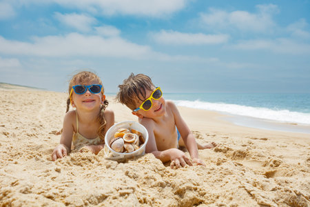 Kids enjoying beach time, collecting seashells under the sunの写真素材