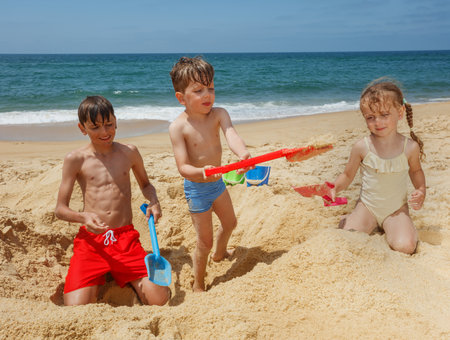 Happy kids digging in the sand at beach with playful enthusiasmの写真素材