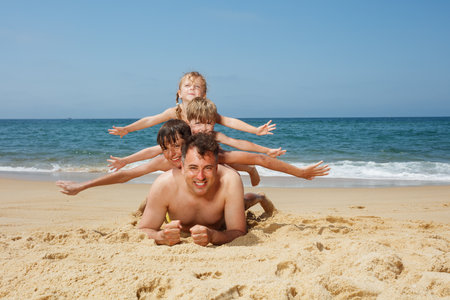 Family enjoy a fun day at the beach with playful sand activitiesの写真素材