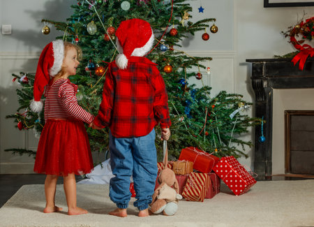 Kids enjoy magic of Christmas, gazing at the festive xmas treeの写真素材