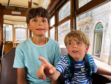 Happy boy point outside window during fun tram ride in Lisbonの写真素材