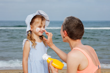 Fun of applying sunscreen on a child during day at the beachの写真素材