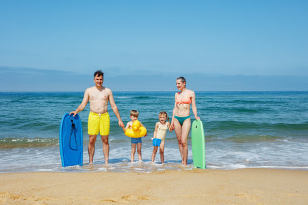 Family of four gearing up to make waves at the beach in summerの写真素材