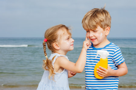 Siblings putting sunscreen on each other at seaside vacationsの写真素材