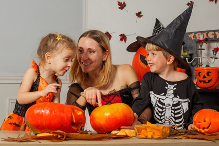 Family enjoying Halloween activities, carving pumpkins togetherの写真素材