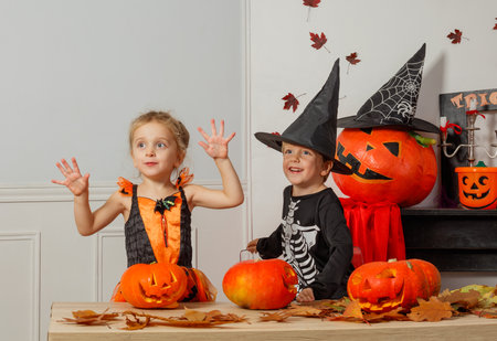 Kids in Halloween costumes pose with pumpkins and autumn leavesの写真素材