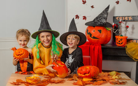Children in Halloween costumes enjoying pumpkin carving togetherの写真素材