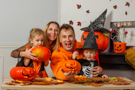 Happy family gathers to celebrate Halloween with carved pumpkinsの写真素材