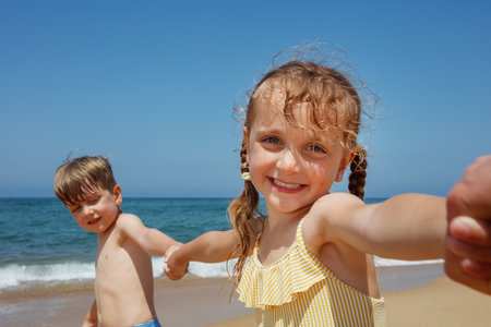 Happy children holding hands, enjoying a bright day at the beachの写真素材