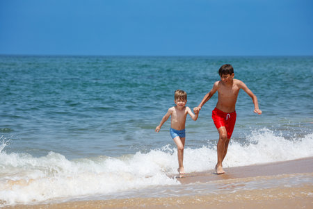 Happy children running on a beautiful beach, enjoying summer funの写真素材