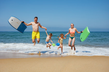 Ready for beach fun, family happily stands at the edge of shoreの写真素材
