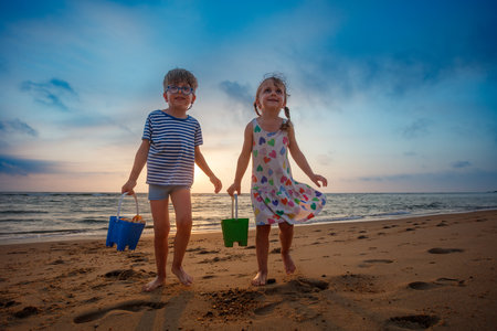 Two kids play on beach at sunset, enjoying perfect summer dayの写真素材