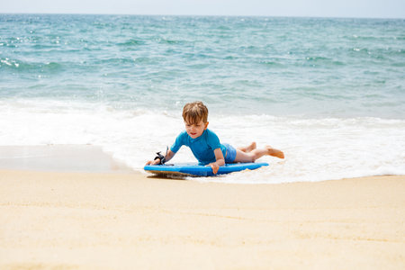 Young boy on a beach enjoying bodyboarding in the ocean wavesの写真素材