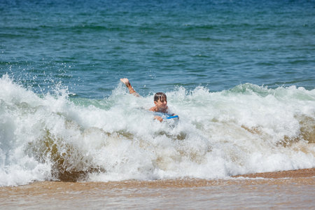 Teenager enjoys bodyboarding in the ocean waves on sunny dayの写真素材
