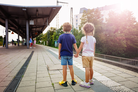 Young boy and girl watching a red train arrive at the stationの写真素材