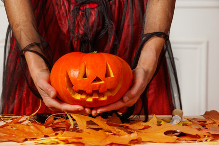 Hands of woman in dress hold happy jack-o-lantern for Halloweenの写真素材