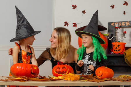 Mother and kids, dressed in Halloween costumes, carve pumpkinsの写真素材