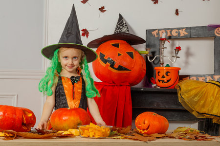 Little girl smile in a witch costume with Halloween pumpkinsの写真素材
