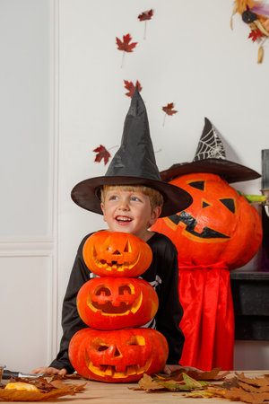 Boy with jack-o-lanterns and witch hat having Halloween funの写真素材