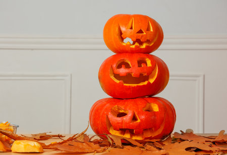 Halloween pumpkins carved into creative faces placed in a stackの写真素材