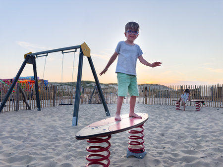 Kids playing at a beach playground, enjoying the evening sunsetの写真素材