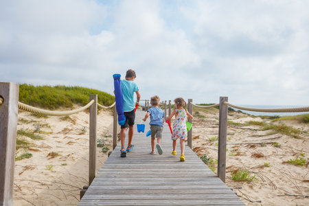Heading to beach, kids and teenager carrying shovels, bucketsの写真素材
