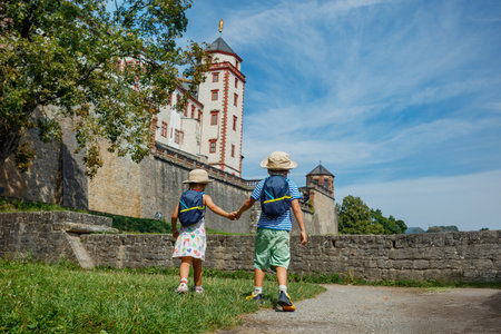 Holding hands, two kids walk along a path in Marienberg Fortressの写真素材