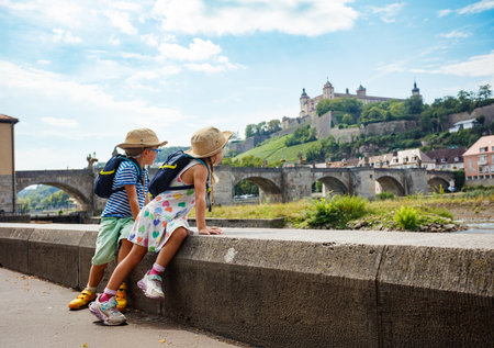 Kids with backpack enjoy beautiful river view and ancient bridgeの写真素材